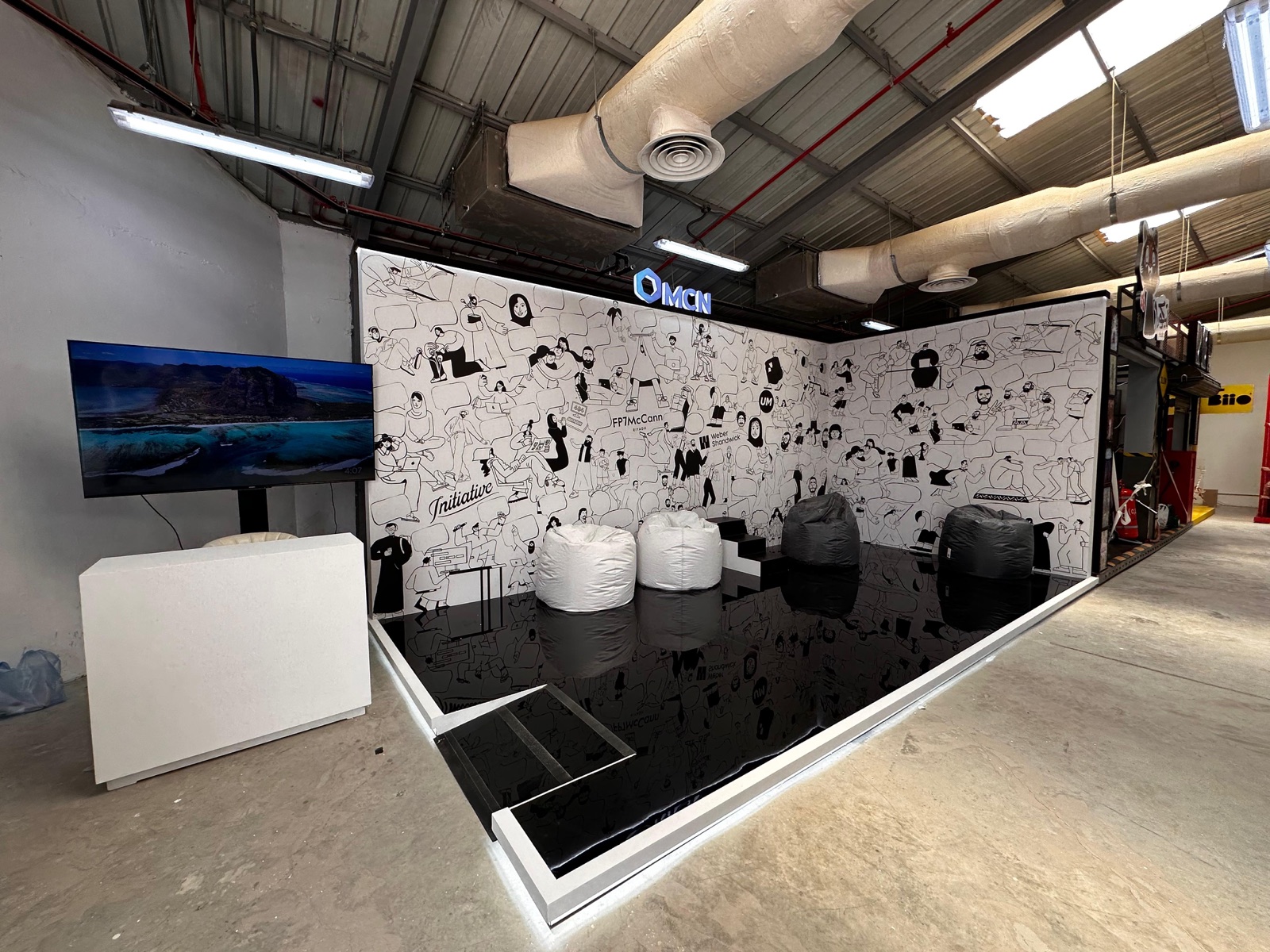 Custom exhibition booth with illustrated brand wall, LED screen and seating area installed by Darb Productions in Riyadh