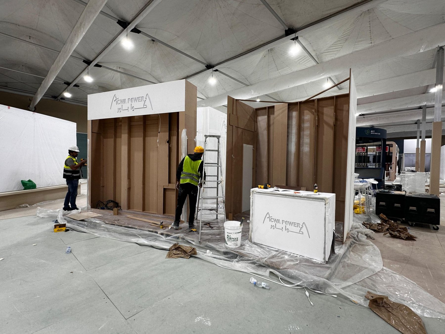 Exhibition booth structure mid-build with its fascia already fitted, inside a Riyadh pavilion